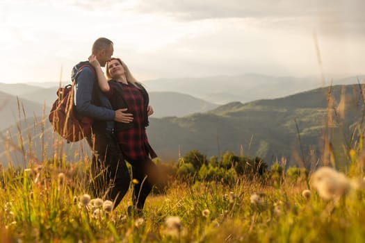 Man and woman standing and hugging on the top of the mountain, autumn hike with backpacks.