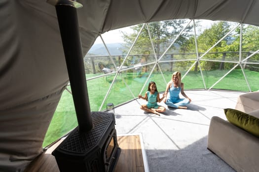 mother and daughter yoga in a glamping dome tent.