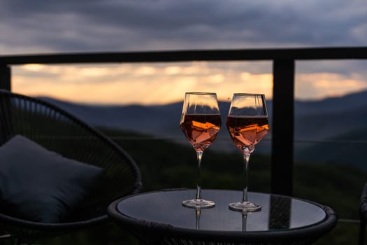 Two glasses of wine standing with a beautiful scenic mountain view. Mountain resort, enjoy moment.