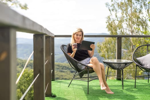 a woman with a tablet on a terrace in the mountains