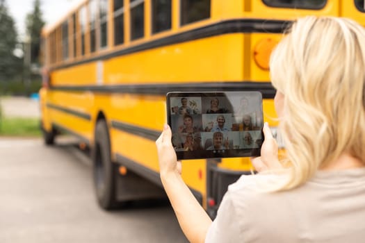 Female Teacher Or Student With Digital Tablet near the school bus. video chat.