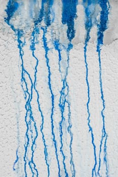 Streaks of liquid spilled blue paint down the white plaster wall abstract pattern dirty background design.