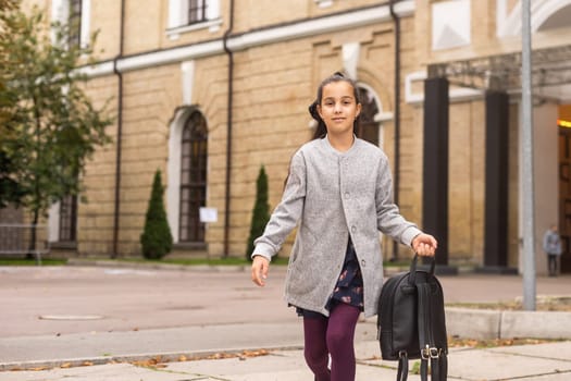 Cute young girl with a backpack heading to school on cold autumn morning