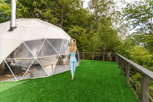 a woman is doing exercises on the terrace of a transparent bubble dome.