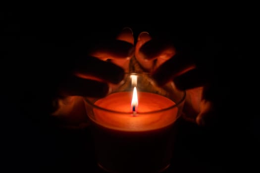 Close up of woman hand lighting candles in the dark night at home.