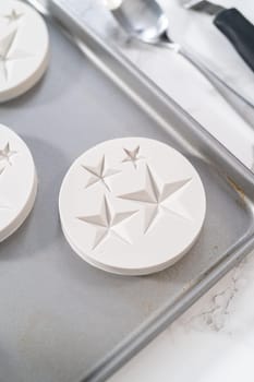 Filling silicone mold with white melted chocolate to make chocolate chocolate stars for American flag mini cupcakes.