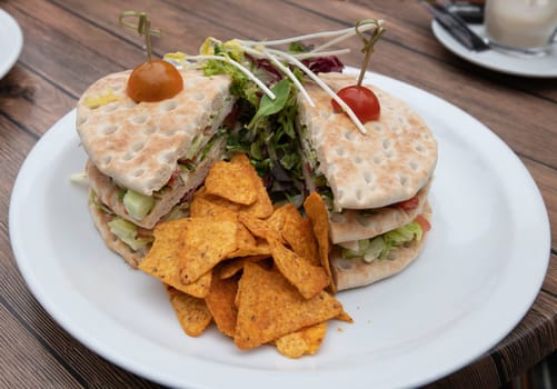 sandwich on a plate served with tomato olive lettuce bacon chicken and fresh lettuce on a bread