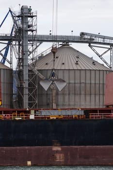 Loading sand onto a cargo barge in a seaport close-up