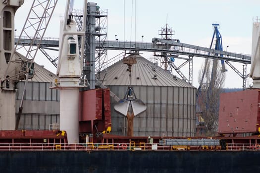 Loading sand onto a cargo barge in a seaport close-up