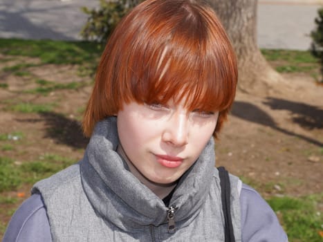 portrait of a smiling red-haired teenage girl in sunlight.