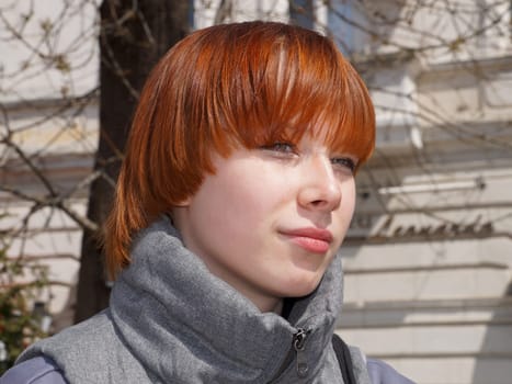 portrait of a smiling red-haired teenage girl in sunlight.