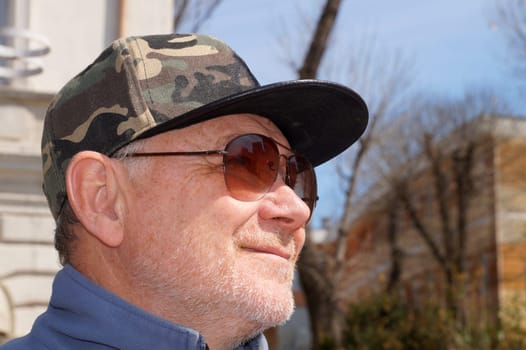 smiling man in cap and sunglasses close up.