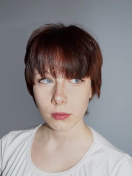 portrait of a teenage girl with short brown hair on a gray background.