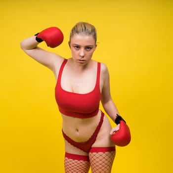 Seductive young and fit female fighter posing in gloves in a studio