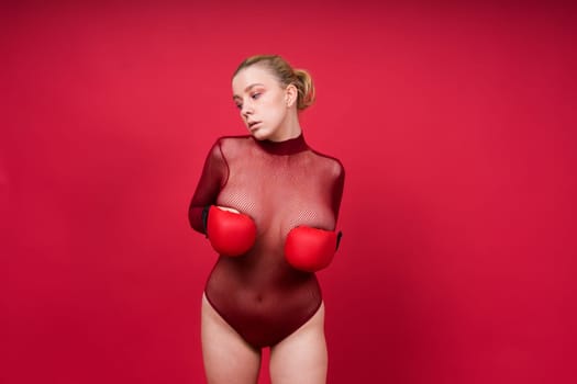 Seductive young and fit female fighter posing in gloves in a studio