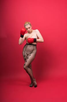 Seductive young and fit female fighter posing in gloves in a studio