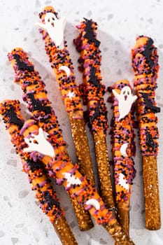 Flat lay. Halloween chocolate-covered pretzel rods with sprinkles on a kitchen counter.