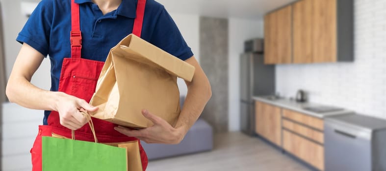 Young handsome delivery man holding paper bag with takeaway food happy with big smile