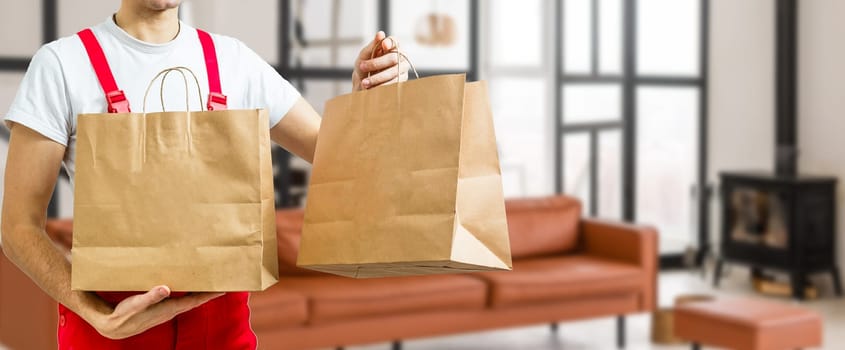 Paper pocket and food containers in hands of a smiling deliveryman. .Quality service of a restaurant