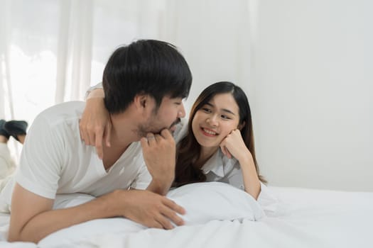 Asian Romantic couple in bed enjoying sensual foreplay Happy sensual young couple lying in bed together. Beautiful loving couple kissing in bed