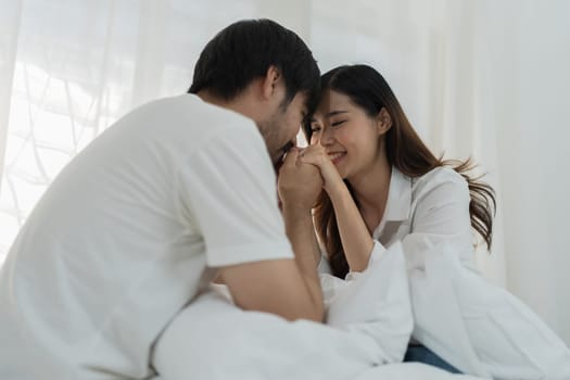 Asian Romantic couple in bed enjoying sensual foreplay Happy sensual young couple lying in bed together. Beautiful loving couple kissing in bed