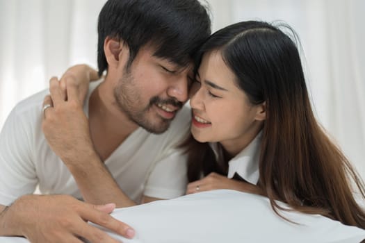 Asian Romantic couple in bed enjoying sensual foreplay Happy sensual young couple lying in bed together. Beautiful loving couple kissing in bed