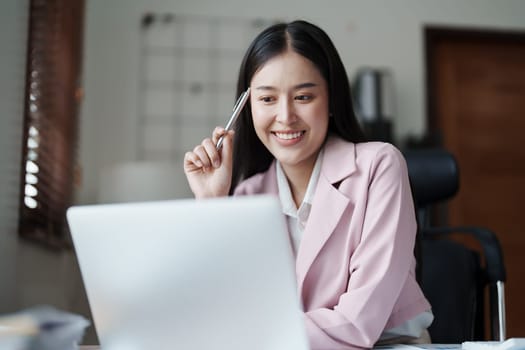 Portrait of a woman business owner showing a happy smiling face as he has successfully invested her business using computers and financial budget documents at work.