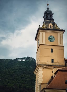 The council house clock tower with a beautiful view to the Brasov sign on top of the hill. Popular tourist location in Romania