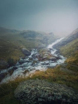 Mountain stream flowing fast across a rocky valley in Fagaras Mountains. River with high water debit during the rainy season