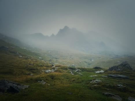 Mountain peak seen through the dense fog. Rainy scene in the mounts, hiking in the mist landscape