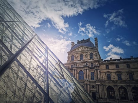 Louvre building, outdoors facade view of the famous museum palais with the modern glass pyramid in Paris, France