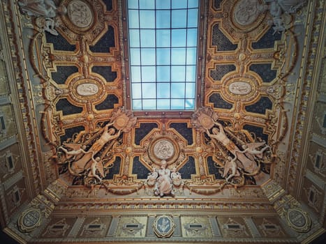 Golden ceiling with architectural details of the Salon Carre inside Louvre museum, Paris, France. Gilded ornaments with sculptures dedicated to Murillo and Poussin