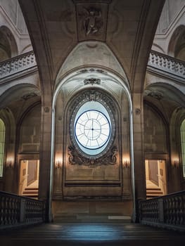 Louvre Palace symmetric architectural details of a hall with stone staircase, ornate railings, different corridors and a clock type window in center, Paris, France