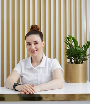 Female receptionist at reception desk in modern office lobby