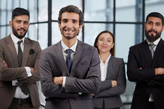 portrait shot of smiling business team of four standing and smiling at camera against a modern office background
