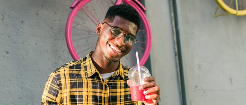 Young cheerful african american male on city having fun and holding cocktail. Man on summer holiday. Leisure lifestyle holiday and summer drinks concept.