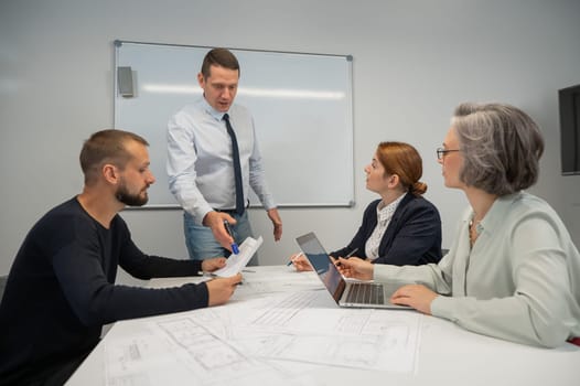 Caucasian man leading a presentation to colleagues at a white board