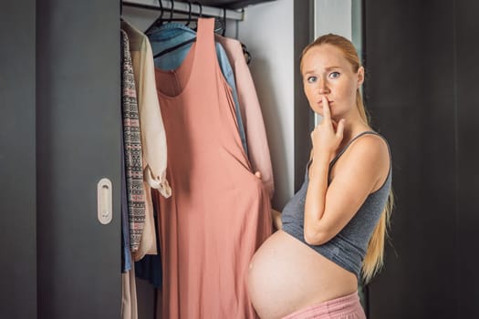 A pregnant woman has nothing to wear. A pregnant woman stands in front of a closet with clothes and does not know what to wear because the clothes do not fit on her.