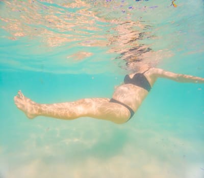 Pregnant woman underwater swimming in tropical sea. Healthy and active pregnancy. Young expecting mom on summer beach vacation before baby birth. Swim holiday and water fun. Travel during pregnancy. Underwater photography.