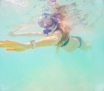 Pregnant woman underwater swimming in tropical sea. Healthy and active pregnancy. Young expecting mom on summer beach vacation before baby birth. Swim holiday and water fun. Travel during pregnancy. Underwater photography.