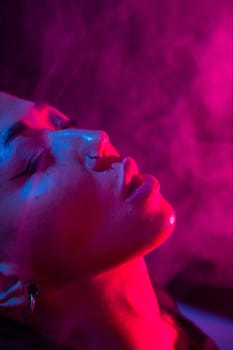 Asian woman with short haircut smoking in neon light. close-up portrait