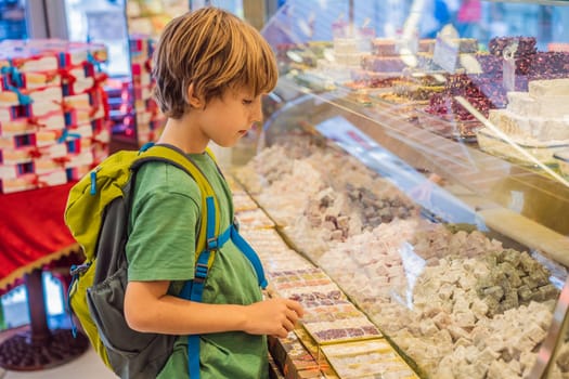 The boy looks at the counter with Turkish sweets. Traditional oriental sweet pastry cookies, nuts, dried fruits, pastilles, marmalade, Turkish desert with sugar, honey and pistachio, in display at a street food market.