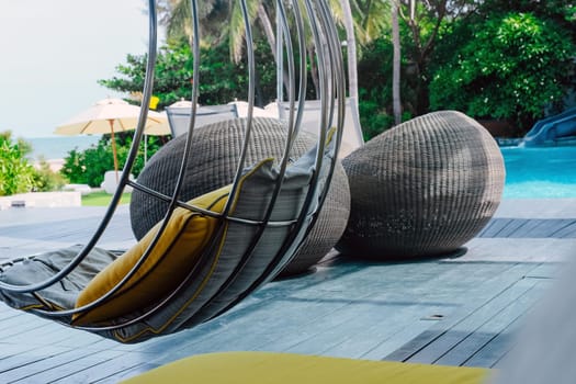 Image of Relaxing chairs with pillows beside swimming pool