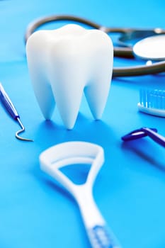 Tooth model and dentist tools on blue background. Dentistry concept.
