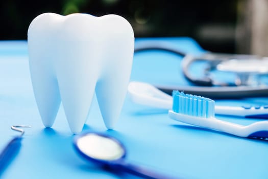 Tooth model and dentist tools on blue background. Dentistry concept.