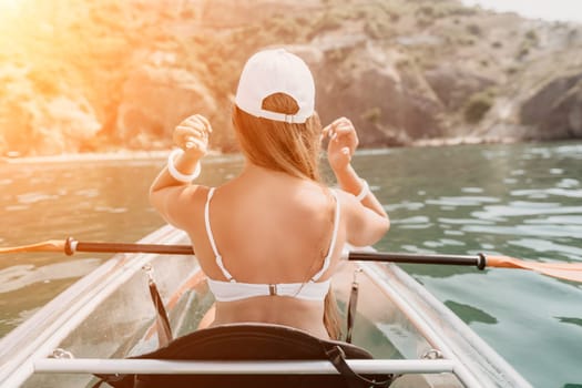 Woman in kayak back view. Happy young woman with long hair floating in transparent kayak on the crystal clear sea. Summer holiday vacation and cheerful female people having fun on the boat.