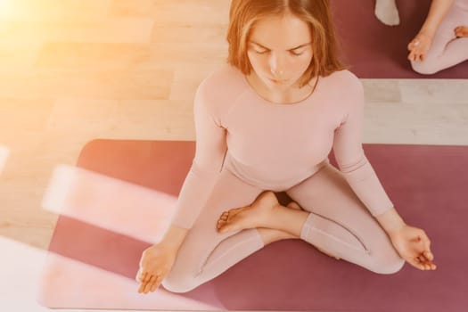 Young woman with long hair in white swimsuit and boho style braclets practicing outdoors on yoga mat by the sea on a sunset. Women's yoga fitness routine. Healthy lifestyle, harmony and meditation