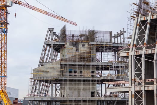 Construction of a large concrete building. Construction crane on the background of the sky. Construction site.