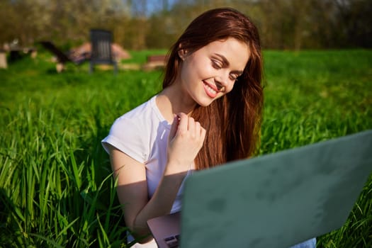 happy, joyful woman working on a laptop while sitting in a field. High quality photo
