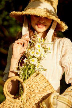 close portrait of a smiling woman in a wicker hat covering her face, holding a wicker basket full of daisies. High quality photo
